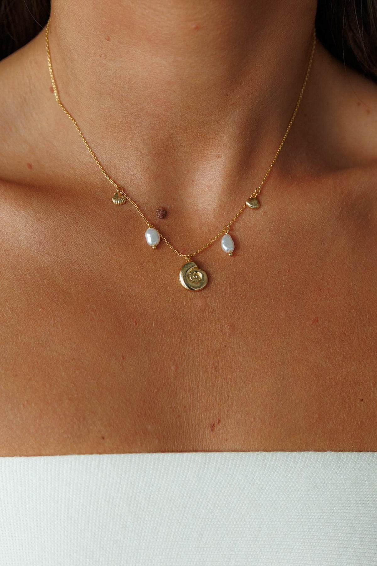 Shell and Pearl Charm Necklace, worn at the neck over a cream top