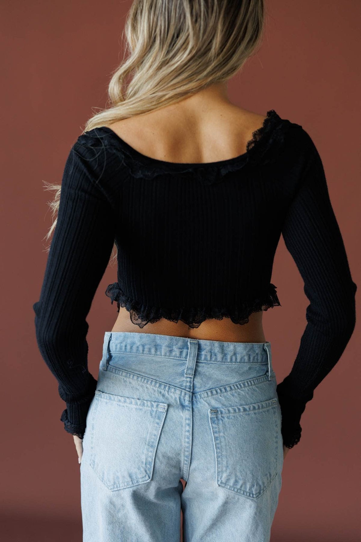 Colette Ruffle Top in black, back view showing the ribbed knit and ruffle hem