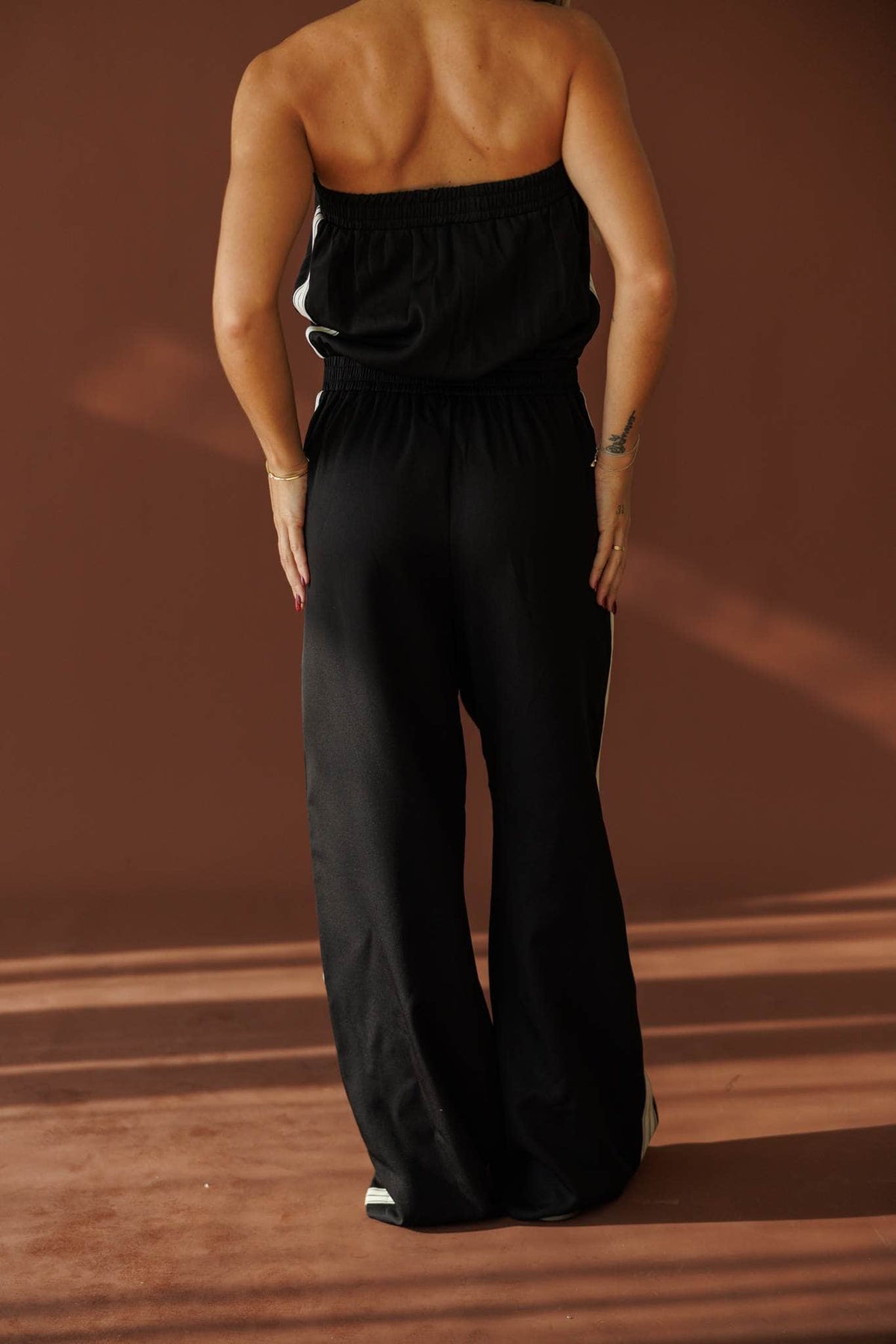 Curtain Call Jumpsuit in black, back view showing the strapless jumpsuit