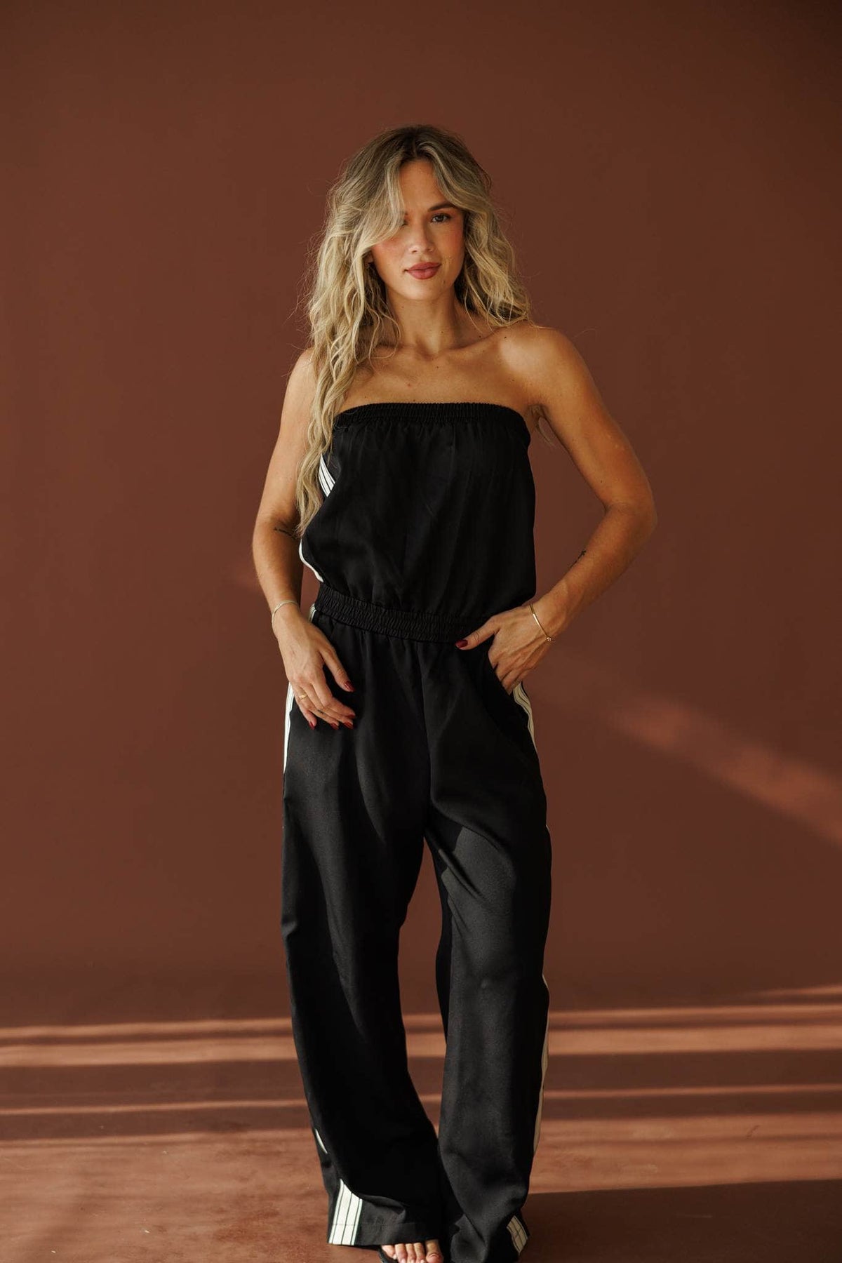Curtain Call Jumpsuit in black, full-length view with a hand on the hip