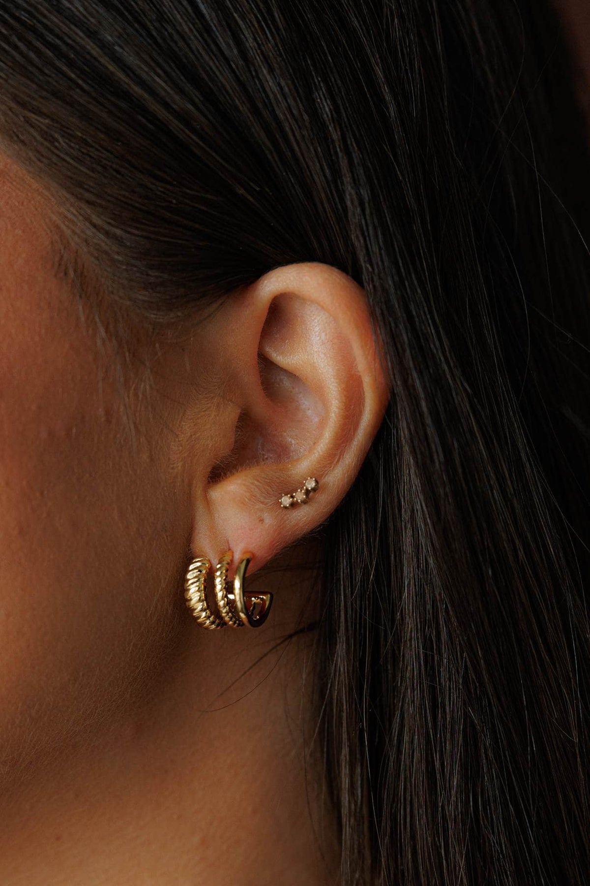 Gold Petite Hoop Trio, worn across a second and third piercing