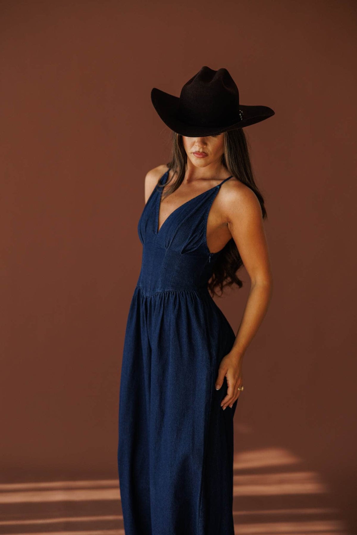 Miles From Home Jumpsuit in dark denim, front view on model with a hand at the hip