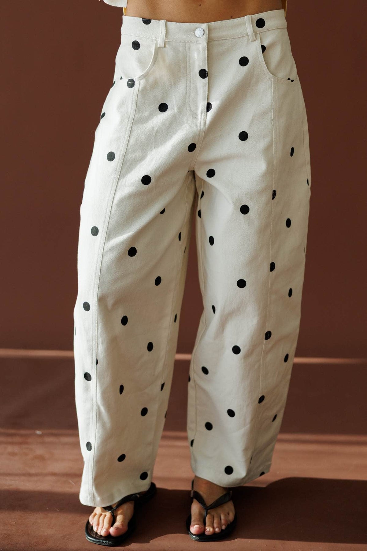 On The Dot Barrel Pants in cream and black dot, front close-up of the button front and barrel leg