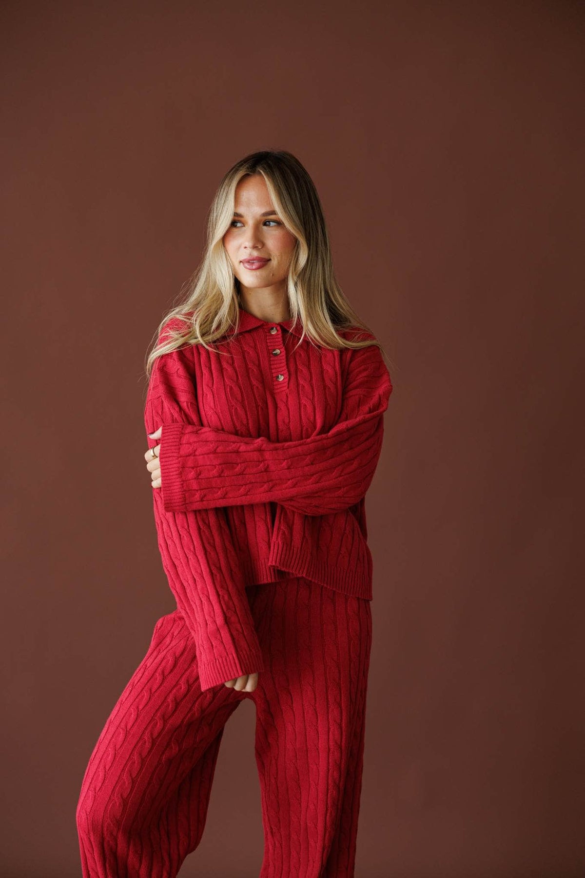 Cherry Cable Knit Sweater in red, front view on model with arms crossed