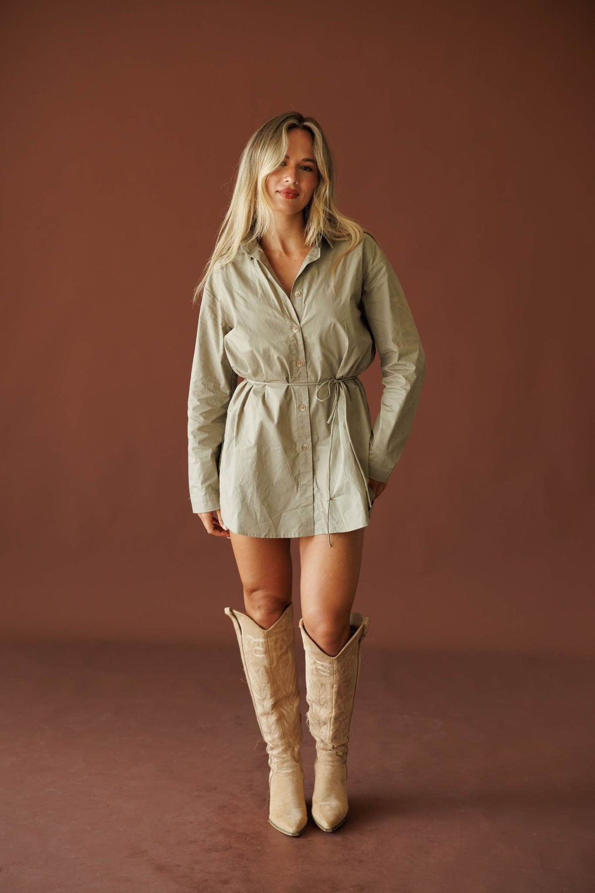 Western Chic Shirt Romper in muted olive, full-length view with tall cream boots