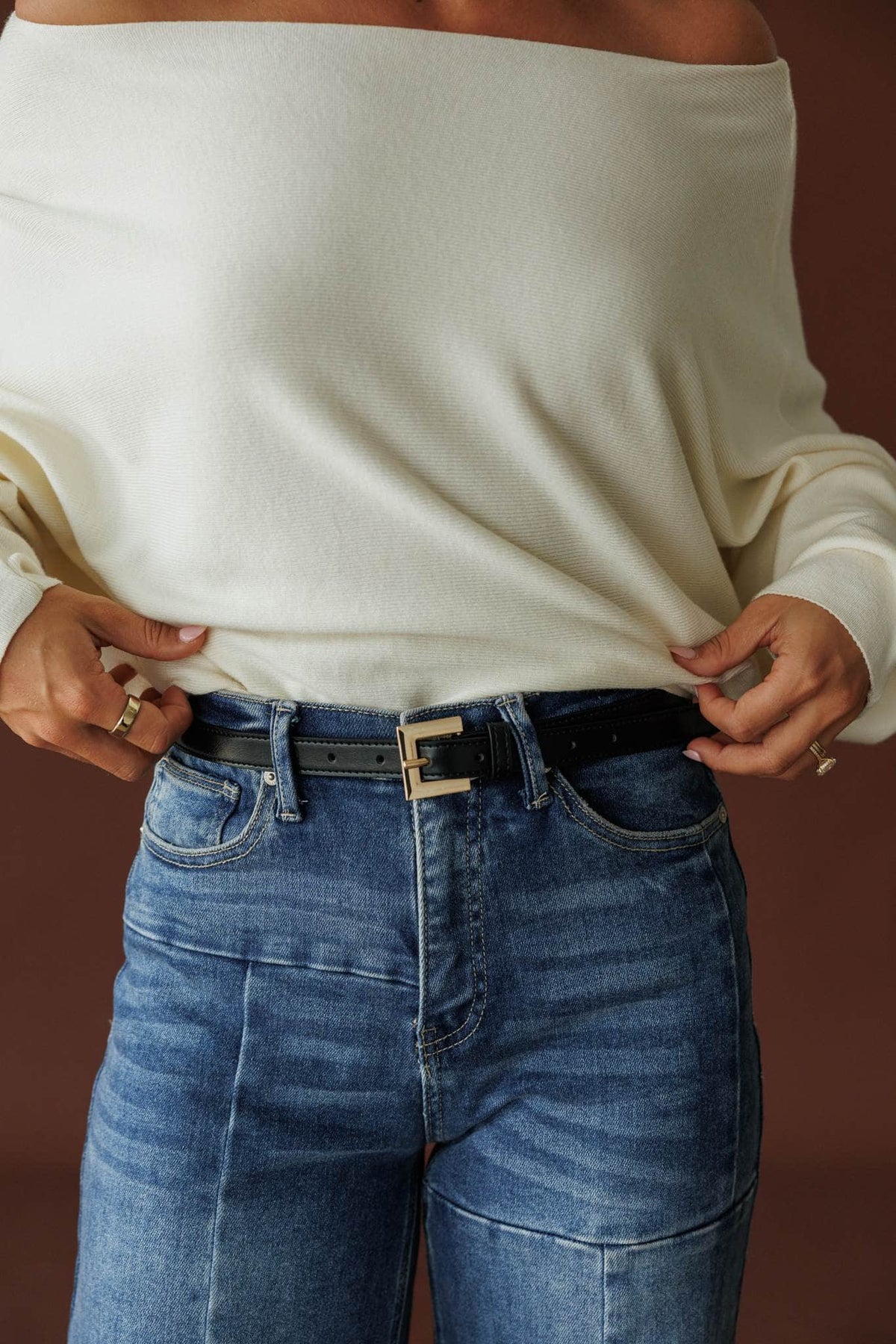 Jordan Belt, in black shine, close front view of the belt and gold buckle over denim