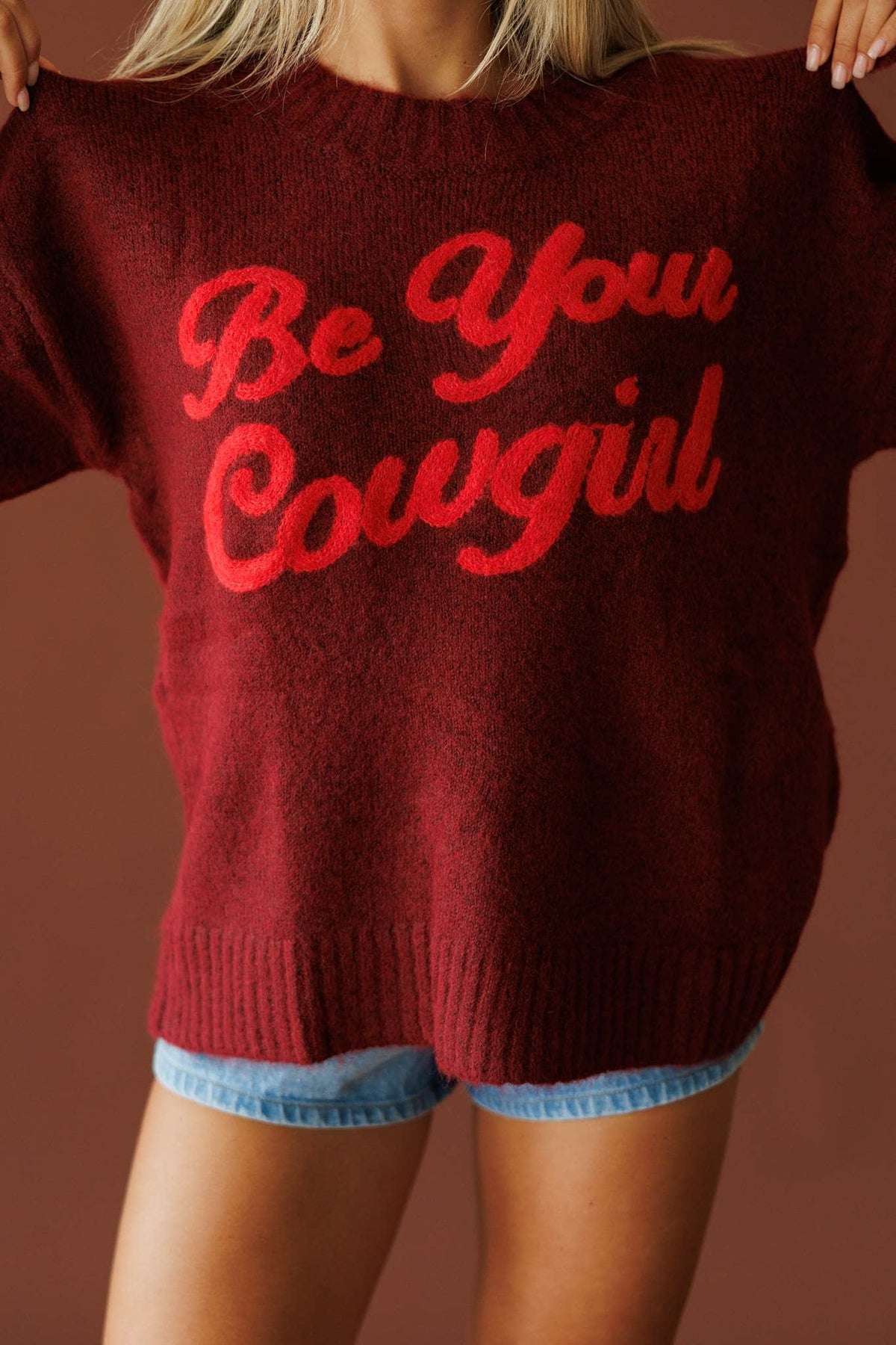 Be Your Cowgirl Sweater in burgundy, front close-up of the red BE YOUR COWGIRL script